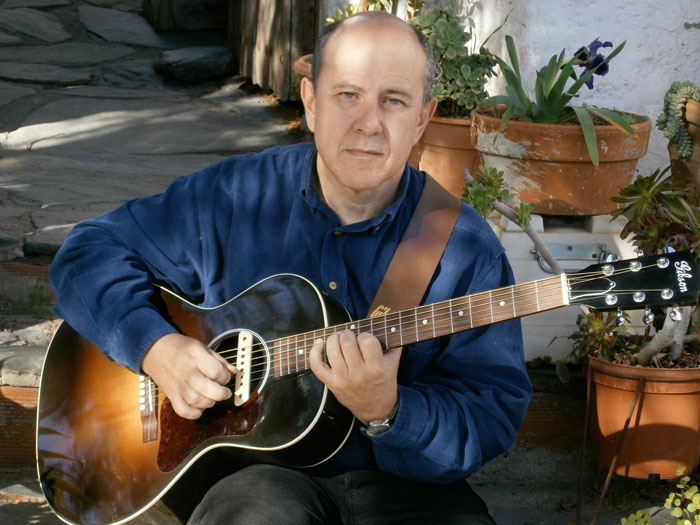 Ramon Leal tocando la acústica, mirando a la cámara con aire inspirado